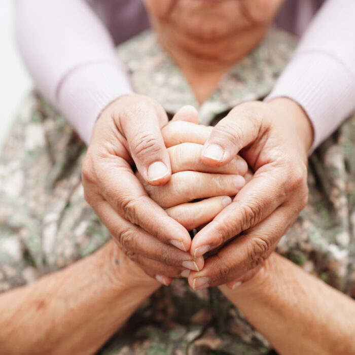 carer's hands encircling an elderly woman's hands