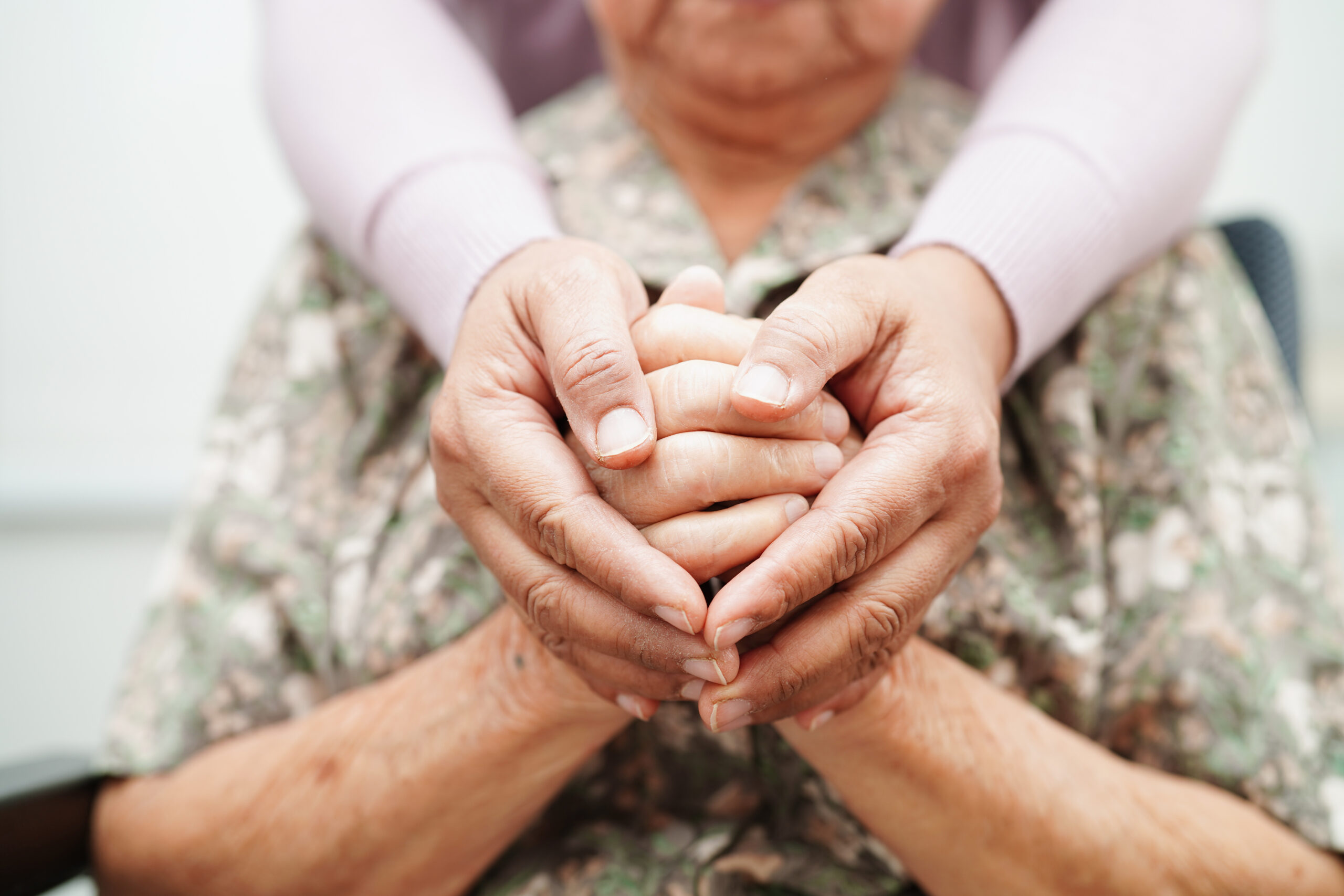 carer's hands encircling an elderly woman's hands
